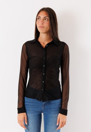 Camicia nera trasparente con maniche lunghe e bottone frontale, caratterizzata da un colletto classico e polsini neri a contrasto. Texture liscia con una silhouette aderente.