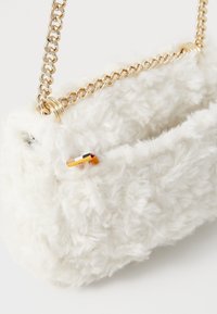 Bela umetna krznena torbica z zlatim verižnim trakom, ki ima teksturirano površino in majhen večbarvni detajl na strani.