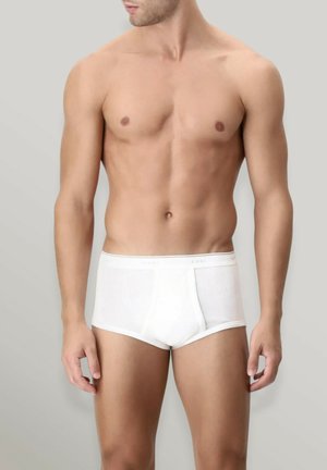 Slip in cotone bianco con texture a coste, dotato di una fascia in vita con logo e design aderente. Modello mostrato su uno sfondo neutro.