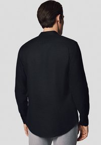 Czarna koszula z długim rękawem, wykonana z lekkiego materiału, z zaokrąglonym dołem i mankietami na guziki. Prosty design bez wzorów czy akcentów.