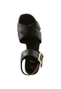 Černá kožená sandál s překříženými pásky a zlatou sponou. Podešev je plochá, s texturovaným povrchem a minimalistickým designem.