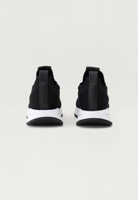 Melnas sporta kedas ar strukturētu auduma virsotni, baltu starppodolu un melnu ārējo zoli. Iezīme ir izturīgs papēža cilpiņa, kas nodrošina ērtu uzvilkšanu.