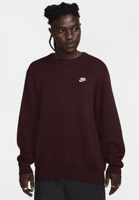 Bordeaux strikket sweatshirt med rund hals og lange ærmer. Har et hvidt Nike-logo på brystet. Blød tekstur og afslappet pasform.