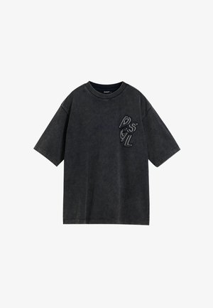 Camiseta negra de gran tamaño hecha de algodón suave, con mangas cortas, cuello redondo y detalle de logo en relieve en el lado izquierdo del pecho.