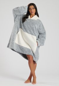 Sudadera gris de felpa de gran tamaño con una suave capucha forrada de fleece blanco y un bolsillo blanco en contraste. Presenta mangas largas y un ajuste relajado.