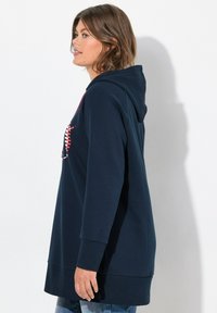 Felpa con cappuccio navy a maniche lunghe, con orlo curvo e un design grafico colorato sulla parte anteriore. Realizzata in tessuto morbido.