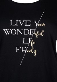 Sort bomulds t-shirt med hvid og guld tekst, der står "LEV DIT VIDUNDERLIGE LIV FRIT" med et diagonalt design, der adskiller sætningerne.