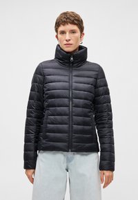 Melnā pūkainā jaka ar augstu apkakli, izšūtu dizainu, rāvējslēdzēja aizdari un sānu kabatām. Izgatavota no viegla, spīdīga materiāla.