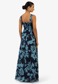 Abito lungo con sfondo navy e stampa floreale blu, dotato di spalline larghe e schiena arricciata per comfort e vestibilità.