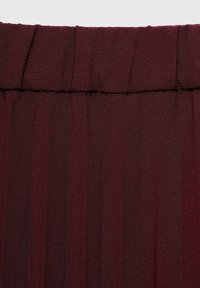 Tessuto plissettato borgogna con una textura liscia, caratterizzato da una vita arricciata e pieghe uniformi che esaltano il design.