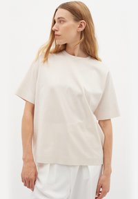 Ljusbeige kortärmad t-shirt i en mjuk bomullsmix, med rund halsringning och avslappnad passform samt en jämn, minimalistisk textur.