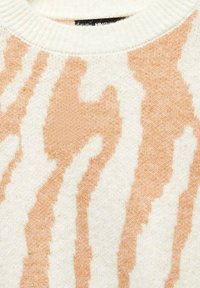 Suéter chunky con una base crema y un llamativo patrón de rayas de cebra en melocotón, cuello acanalado y una textura suave.