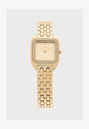 Goldene Armbanduhr mit quadratischem Zifferblatt, mit Kristallen besetzter Lünette, goldenem Zifferblatt und verbundenem Metallarmband, die Uhrzeit 10:11 anzeigend.
