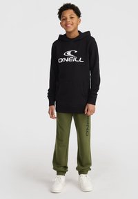 Hoodie noir avec logo blanc "O'Neill", poche kangourou, associé à un pantalon vert olive avec logo sur le côté, complété par des baskets blanches.
