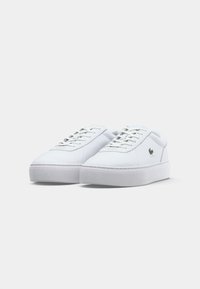 Sapatilhas de couro branco com bico arredondado, design com cordões e sola de borracha branca espessa. Pequeno detalhe do logotipo no lado exterior. Textura suave.