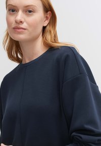 Felpa blu navy realizzata in tessuto morbido, con scollatura rotonda, spalle scese e una vestibilità rilassata con cuciture minime.