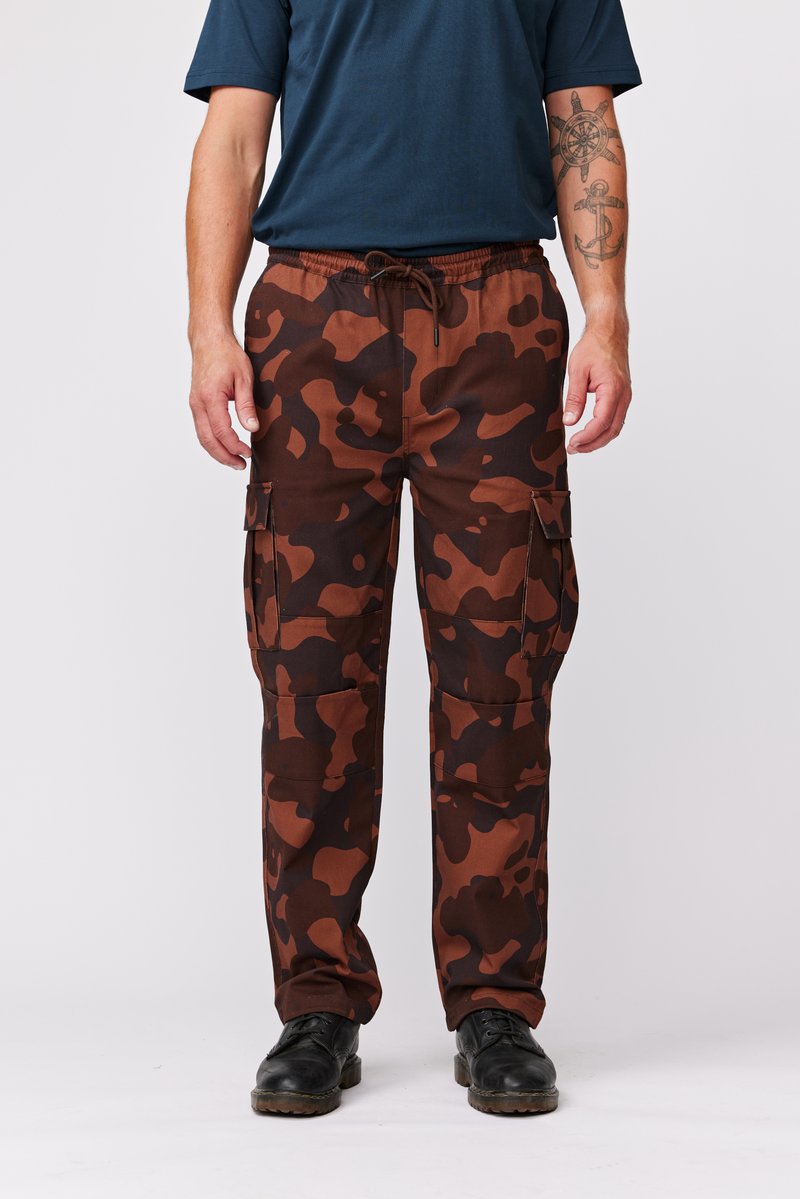 Brune camouflage cargo bukser med elastisk talje, snøre og flere lommer. Båret med sorte sko.