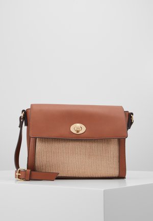 Sac en bandoulière en cuir marron et en rotin tressé, avec un fermoir à tourniquet doré et une bandoulière en cuir réglable sur une surface blanche.