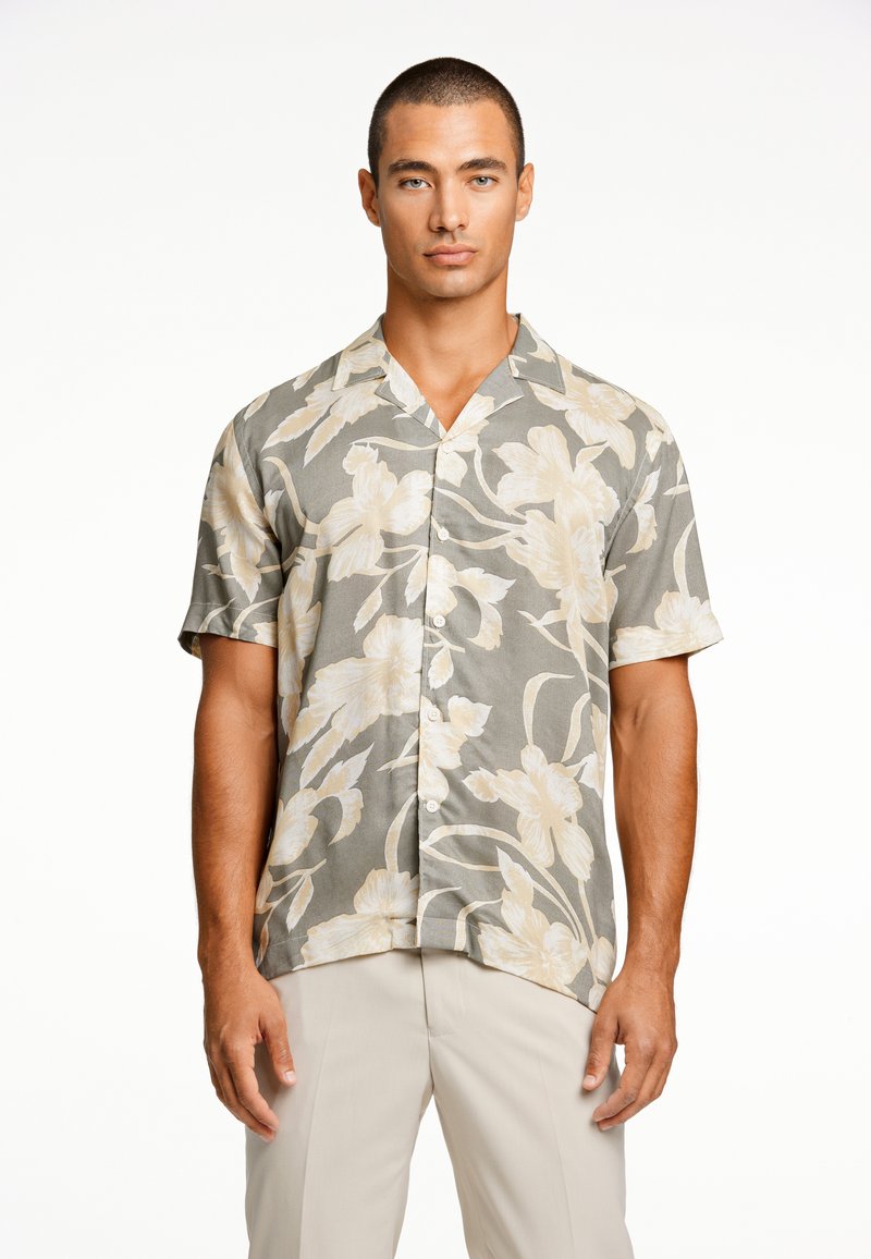 Camisa de botones de manga corta en un fondo gris con grandes patrones florales en color crema, que cuenta con un cuello tipo campamento y una tela ligera.
