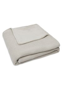 Beige deken met een textuur brei aan de ene kant en een zachte, gladde stof aan de andere kant, netjes opgevouwen met een contrasterende rand.