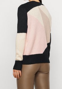 Strickpullover in Schwarz, Creme, Hellrosa und Taupe mit geometrischen Mustern; gerippte Bündchen und Saum; strukturierte Wolle; lässige Passform.