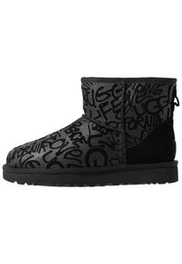 Botín negro de longitud hasta el tobillo con una superficie brillante que presenta un patrón texturizado de diversas escrituras en negro, complementado por un tacón de ante negro.