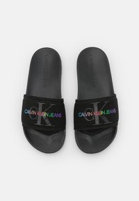 Černé pantofle na klínku s texturovaným černým páskem s vícenásobným barevným logem "CALVIN KLEIN JEANS" a hladkými černými gumovými podrážkami.