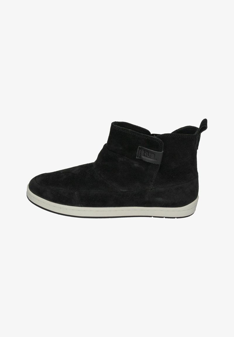 Black suede ankle boot with a rounded toe, white sole, and a side strap featuring a logo. Smooth texture with a mid-height design.