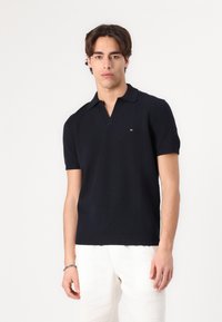 Kurze Ärmel Poloshirt aus marineblauem Strick mit V-Ausschnitt und geripptem Kragen, mit einem kleinen Logo-Detail auf der linken Brust.