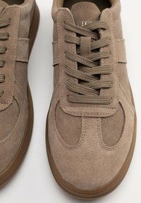 Braune Wildledersneaker mit runder Zehenpartie, flachen Schnürsenkeln und Gummisohle. Verfügt über gestickte Akzente und eine gepolsterte Zunge für zusätzlichen Komfort.