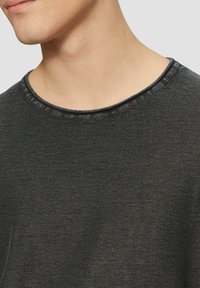 Donkergrijze sweatshirt met ronde hals, gemaakt van een textuurstof met een subtiele glans en versterkte stiksels langs de halslijn.