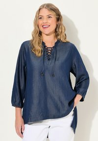 Camicia di denim blu navy con scollatura a V e dettagli con lacci, maniche a tre quarti e orlo arrotondato con spacchi laterali. Tessuto morbido.