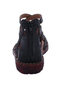 Svarta läderankel sandals med utskärningsdesign, dragkedjestängning bak och brun texturerad sula. Sömnadsdetaljer längs kanterna.