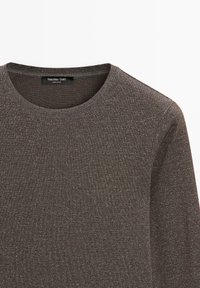 Donkergrijze trui met een ronde hals, gemaakt van gestructureerde stof met een subtiele metallic glans. Label zichtbaar bij de halslijn.