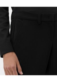 Pantalon noir en tissu lisse, doté d'une taille cintrée avec passants de ceinture, de poches latérales et d'une silhouette ajustée.