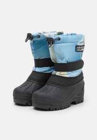 Botas de invierno aisladas en azul con parte superior estampada, suelas de goma negras y parte superior ajustable con cordón para un ajuste seguro.