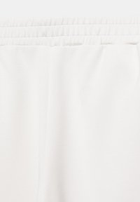 Ceinture élastique blanche avec tissu blanc froncé en dessous, partie d'un vêtement probablement en matière douce.