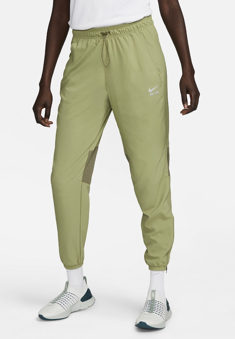 Pantalon de sport vert clair avec une ceinture élastique, des poches latérales et des accents en maille. Présente un petit logo Nike blanc à l'avant.