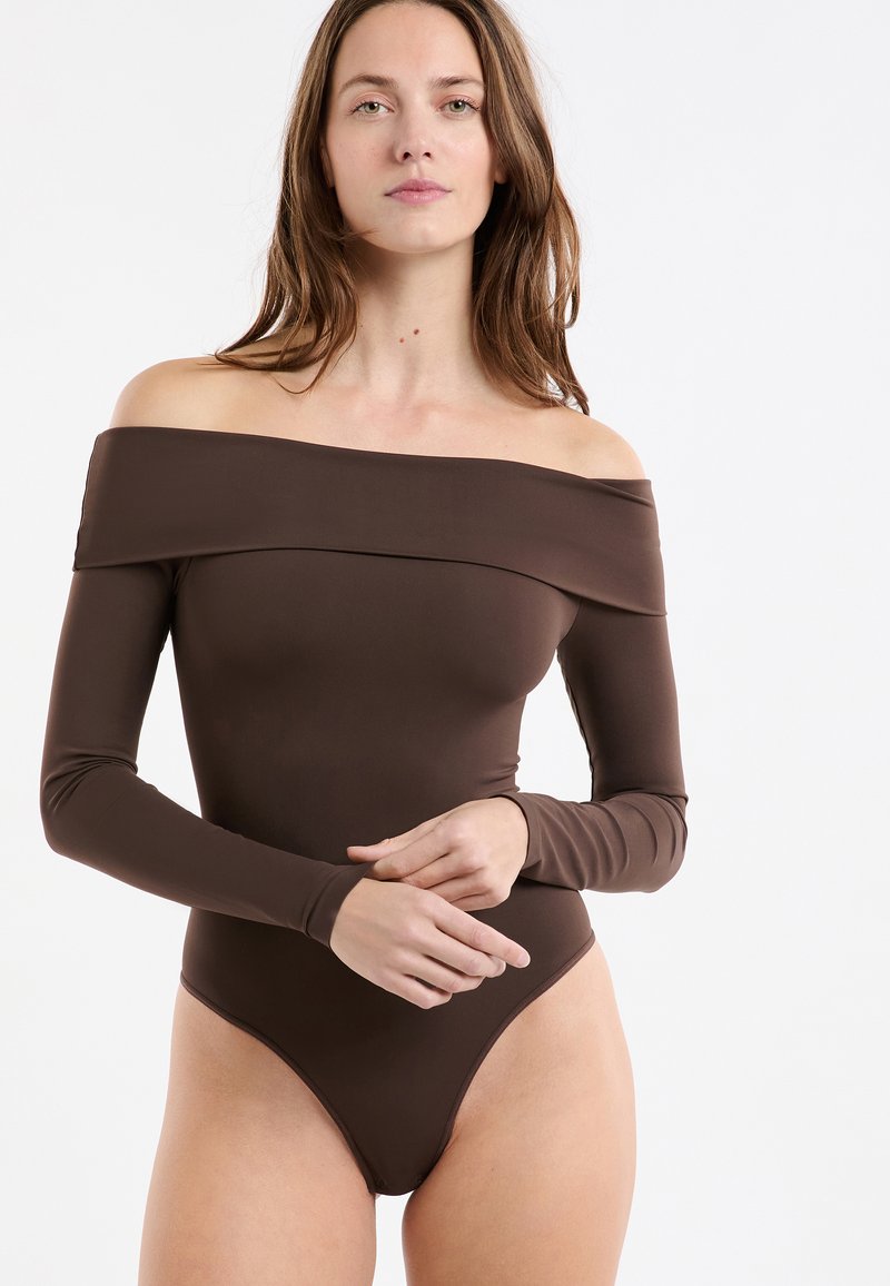 Brązowe body z długim rękawem, odsłaniające ramiona, wykonane z gładkiej tkaniny, o dopasowanym fasonie i wysokim kroju nogawek.