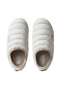 Chaussures blanches matelassées à enfilage, avec des pointes arrondies, une doublure intérieure douce et des languettes au talon. Le logo The North Face est bien mis en avant à l'intérieur.
