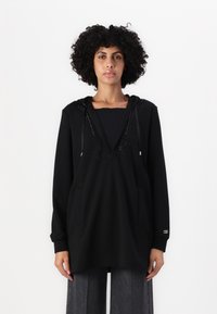 Felpa nera con scollatura a V profonda, decorazioni lungo il colletto, tasche frontali e maniche lunghe. Realizzata in tessuto morbido con una vestibilità comoda.