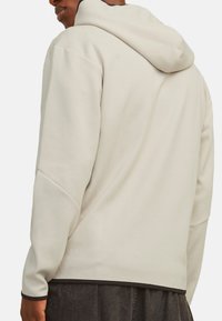 Lichtgrijze hoodie met een ontspannen pasvorm, voorzien van een trekkoordcapuchon, slanke naden en een donkere afwerking aan de zoom en boorden. Glad textuur.
