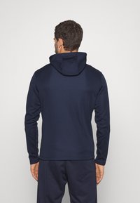 Navy hoodie gemaakt van gladde stof, met een aansluitend ontwerp, lange mouwen en een eenvoudige, strakke silhouet.