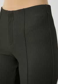 Fekete, bordázott anyagú leggings sima felülettel, magas derékkal és finom varrásokkal, a testhezálló fazon érdekében.