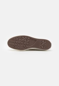 Suela de zapatilla de goma marrón con un diseño de dibujo, borde blanco y punta redondeada. Texturizada para un buen agarre, presenta el nombre de la marca en relieve.