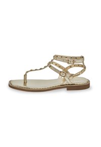 Flat sandals in metallic gold, featuring multiple straps with buckles and stud details, a toe post, and a smooth footbed with a slight heel.