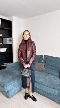 Vyno raudonos odos striukė su užtrauktuku, juodas golfas, džinsinė sijonas su iškirptomis, juodi loaferiai ir mažas juodas rankinukas.