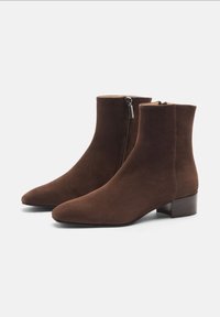 Botas de tobillo de ante marrón con punta afilada, cremallera lateral y un tacón bajo de bloque. Textura suave con un acabado mate.