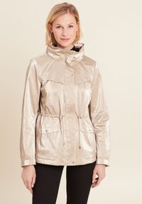 Giacca metallica dorata con colletto alto, vita regolabile con lacci, due tasche frontali e chiusura con zip. Tessuto morbido con una finitura lucida.