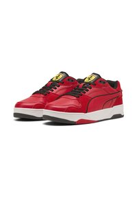 Sneaker in pelle rossa con dettagli neri, dotate di suola bianca e traforature sulla punta. Logo giallo sulla linguetta.
